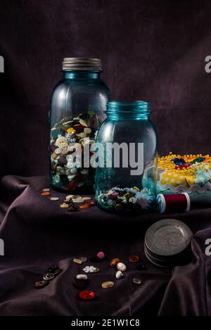 Vintage Canning Flasche oder 'Mason Jar' gefüllt mit alten Knöpfen. Die grünliche und undurchsichtige Farbe des Glases ist ein verräterisches Zeichen alter Glasflaschen. Stockfoto