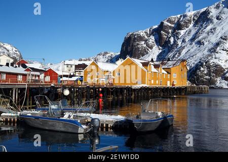 Nusfjord und traditionelle norwegische Holzhaus Rorbu auf dem Ufer des Fjords mit Bergen in der Ferne stehen. Lofoten-Inseln. Norwegen. Stockfoto