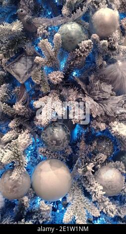 Künstlicher Weihnachtsbaum mit Kugeln und blauen Lichtern, Fragment Stockfoto