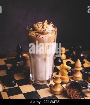 Dalgona Kaffee. Schlagsahngetränk mit Instant-Kaffee beliebt in Korea cremigen Cocktail in hohen Gläsern mit Schach auf Holzchessboard dekoriert Stockfoto