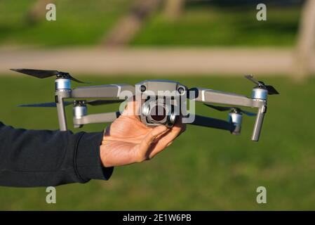 Mann hält graue Drohne draußen im Park. Bereit für den Flug Stockfoto