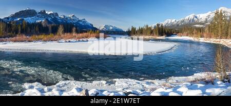 Weite Panoramalandschaft mit Bow River und Snowy Mountain Peaks an einem kalten, aber sonnigen Wintertag in Canmore, Alberta, in der Nähe des Banff National Park Stockfoto