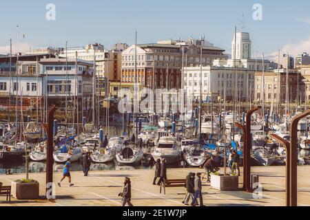 Coruna, Spanien. Allgemeine Ansicht von Menschen, die an einem sonnigen Tag mit einer Maske im Paseo de Parrote mit der Sportbootanlegestelle im Hintergrund spazieren gehen Stockfoto