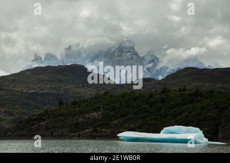 Große Eisberge, die vom Glacier Grey abgekalbt wurden, schwimmen im Wasser des Lago Grey, mit zerklüfteten Gipfeln der Torres del Paine dahinter, Patagonien, Chile Stockfoto