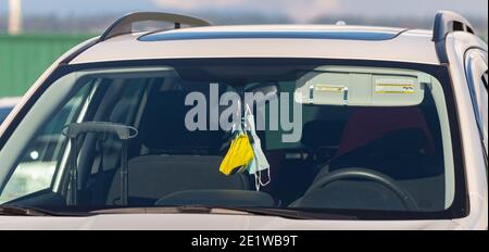 Gesichtsmasken hängen in Auto Innenspiegel. Selektiver Fokus, Straßenfoto. Stockfoto