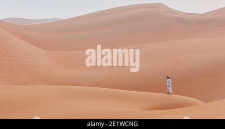 arabischer Mann in Kandoura über einer Düne und schaut zu Der Horizont in der arabischen Wüste Stockfoto