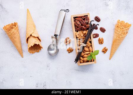Leere Eiszapfen mit gemischten Nuss Setup auf weißem Stein Hintergrund. Sommer und Süße Menükonzept. Stockfoto