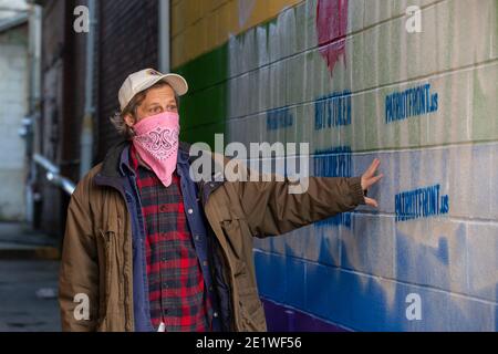 Bryce Taylor, Besitzer von Jake's Cards and Games, schaut sich die weißen nationalistischen Graffiti an, die auf dem Pride-Wandgemälde an der Außenseite seines Unternehmens stehen.Dutzende von Community-Mitgliedern versammelten sich bei Jake's Cards and Games, um das defaced Pride-Wandbild auf der Seite des Unternehmens neu zu malen. Freiwillige wechselten sich ab, um die sprühgemalten Botschaften der weißen nationalistischen Gruppe Patriot Front zu übermalen. Stockfoto