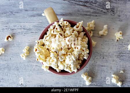 Popcorn in einer weißen Schüssel Draufsicht. Frische Pop Mais in weiß Schlag auf Holz Tisch Hintergrund. Stockfoto