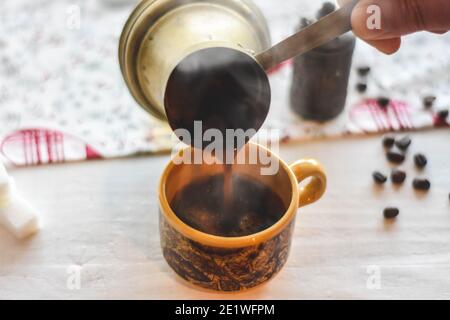 Wake up Kaffee Espresso, Gießen frischen heißen schwarzen Kaffee in die Tasse / Hot schwarzen türkischen Kaffee serviert zum Frühstück Stockfoto