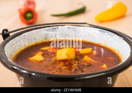 Ungarische Rindergulasch oder Gulyas Suppe oder Eintopf in einem kleinen Kessel mit Kartoffeln, Fleisch, Paprika und Paprika und Chili serviert Stockfoto