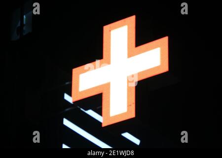 Leuchtendes Pixelkreuz von LED-Lampen auf schwarzem Hintergrund. Orangefarbenes Kreuz mit weißem Zentrum Symbol für Gesundheit, Medizin, Selbstversorgung. Stock Foto mit leerem Spa Stockfoto