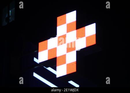 Leuchtendes Pixelkreuz von LED-Lampen auf schwarzem Hintergrund. Kreuz mit einem Muster in weiß und orange Symbol für Gesundheit, Medizin, Selbstversorgung. Stock Foto mit Stockfoto