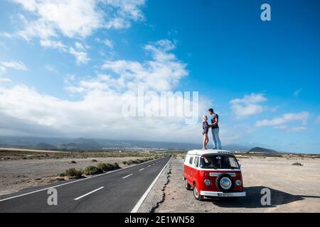 Stehendes Paar auf rotem Dach van Fahrzeug Umarmung und Liebe In Reise-Lifestyle - Konzept der alternativen freien Outdor Urlaub Urlaub mit jungen Leuten und b Stockfoto