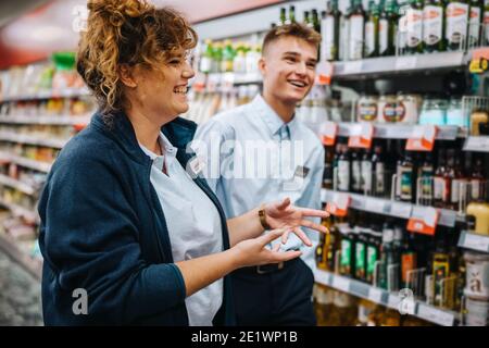 Supermarktmanager, der jungen Arbeitern eine Ausbildung gibt. Lebensmittelgeschäft Manager erklärt den Weg, um einen neuen männlichen Mitarbeiter zu arbeiten. Stockfoto