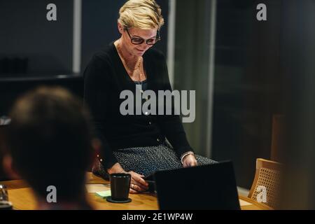 Frau, die während eines Meetings mit einem digitalen Tablet auf einem Konferenztisch sitzt. Geschäftsfrau, die am Tablet-Computer im Büro arbeitet. Stockfoto