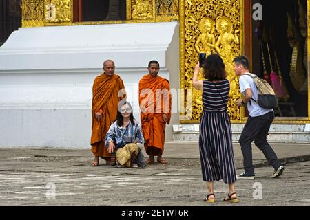 Touristen, die Selfies mit Mönchen am Eingang zum Haus des königlichen Beerdigungchariots, Wat Xieng Thong Tempel, Luang Prabang, Lao machen Stockfoto