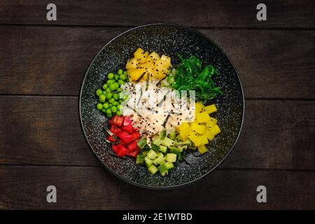 Draufsicht auf Teller mit Salatzutaten - Huhn, Reis, Paprika, Zucchini, Ananas, Gurke, grüne Erbse und chuka Stockfoto