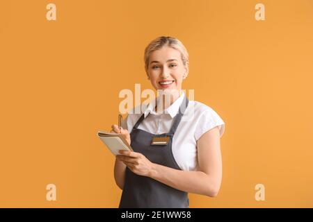 Junge Kellnerin auf farbigem Hintergrund Stockfoto