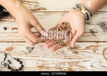 Weibliche Schmuckdesignerin mit Armbändern auf Holzhintergrund Stockfoto