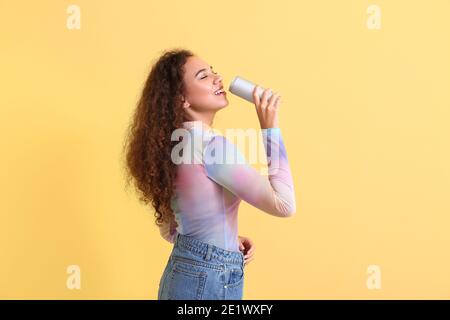 Schöne afroamerikanische Frau mit Soda auf farbigem Hintergrund Stockfoto