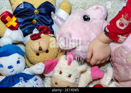 Kleines Mädchen cosset ihr Lieblings Einhorn Spielzeug auf dem Boden Während sie in ihrem Zimmer spielte Stockfoto