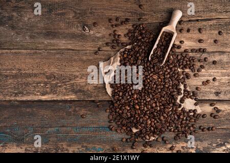 Kaffeebohnen und ein Holzspatel auf einem Holzhintergrund. Stockfoto