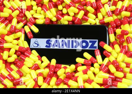 Viersen, Deutschland - 9. April. 2020: Nahaufnahme des Handybildschirms mit Logo-Schriftzug des Pharmaunternehmens Sandoz auf gelber roter Arzneimittelkapsel Stockfoto