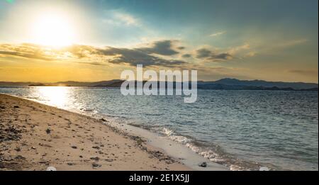 Sandstrand im Komodo Nationalpark bei Sonnenuntergang mit einem Bergkette im Hintergrund Stockfoto