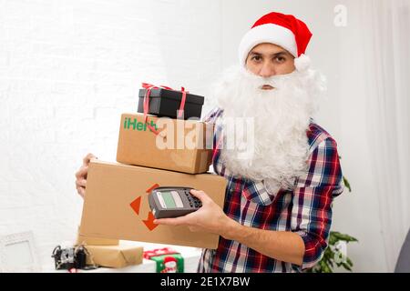 Kiew, Ukraine - 16. Dezember 2020 : Weihnachtsmann mit Geschenkschachteln mit dem Logo der Marke iHerb Stockfoto