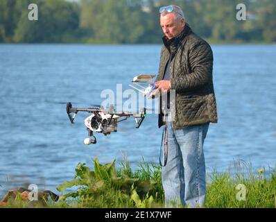 Mann fliegende Drohne, Drohne im Bild, Wasser im Hintergrund. Stockfoto