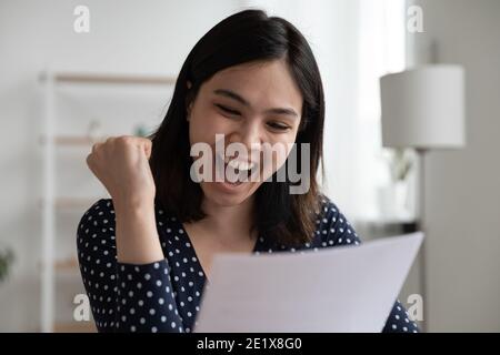 Emotional glücklich asiatische Dame lesen Universität Zulassung Benachrichtigung. Stockfoto
