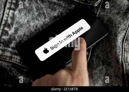 Apple ID Logo auf dem iPhone 11 Bildschirm mit schwarzem und weißem Denim Hintergrund und der Hand einer jungen Frau. Melden Sie sich mit Apple an Stockfoto