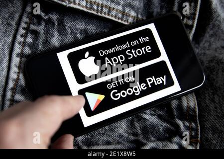 Apple Store und Google Play Marktplätze Symbole, Logo auf dem iPhone 11 Bildschirm mit schwarz-weißen Denim Hintergrund und junge Frau Hand. Stockfoto