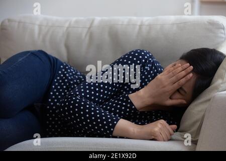 Gestresst frustriert junge asiatische Mischrasse Frau auf Sofa liegen. Stockfoto