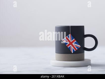 Teebeutel mit Flagge von Großbritannien in grauer Keramik-Tasse auf weißem Hintergrund. Nachmittagstee Tradition Stockfoto