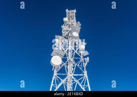Eisbedeckter Zellenturm auf dem Dach der Basis-Funkstation im Hochland. Mobilfunkstation. Wetterstation. Stockfoto
