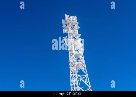 Eisbedeckter Zellenturm auf dem Dach der Basis-Funkstation im Hochland. Mobilfunkstation. Wetterstation. Stockfoto