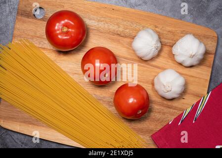Zutaten Tomaten, Knoblauch, Spaghetti für italienisches Essen auf Holzbrett Stockfoto