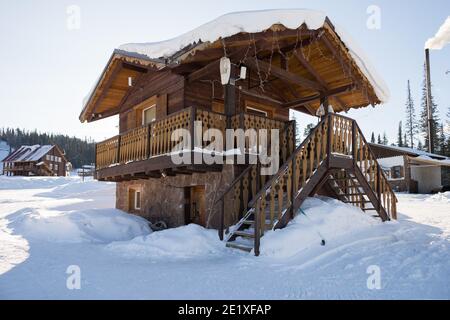 Das Wachhaus steht am Eingang eines Bergdorfes inmitten von Schnee an einem sonnigen Wintertag. Stockfoto