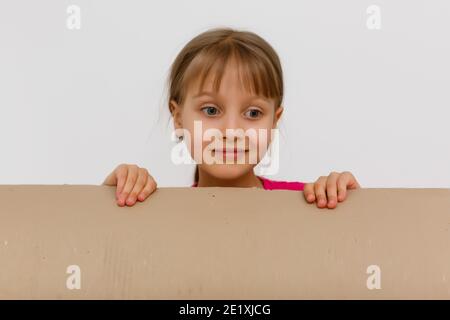 Nettes kleines Mädchen, das in einem großen Karton steht und Verstecken spielen möchte Stockfoto