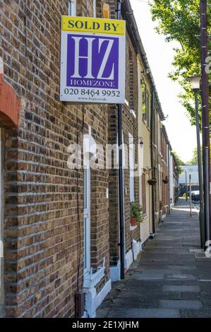 Verkauft Zeichen auf dem Grundstück in einer Straße von kleinen Reihenhäusern. Stockfoto