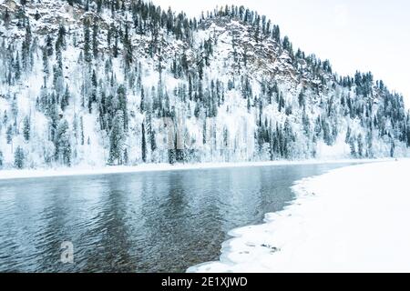 Eisige Ufer des Sees mit verschneiten Wald. Kaltes Wetter, gefrorenes Flussbett aufgrund von scharfem Kälteeinbruch Stockfoto