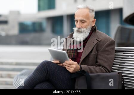 Älterer Geschäftsmann mit langen grauen Bart Lesen auf Pad Stockfoto