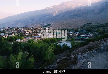 Dorf flankiert von Feldern, See, hohen Himalaya-Bergen und Bäumen im Spiti-Tal bei Sonnenaufgang in Nako, Himachal Pradesh, Indien. Stockfoto