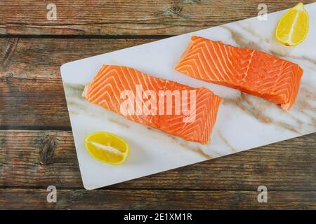 Rohes Lachsfischfilet mit Zitronenscheiben auf Marmor Platine Stockfoto