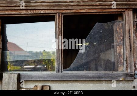 Kaputtes Fenster in einem verlassenen Haus. Beschädigtes Fensterglas Stockfoto