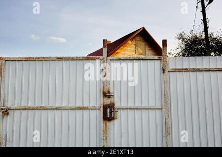 Eiserner rostiger Zaun. Weiße Wellblech oder Zink Textur Oberfläche oder galvanisieren Stahl in der vertikalen Linie Hintergrund. Das Dach des Hauses gegen die Stockfoto