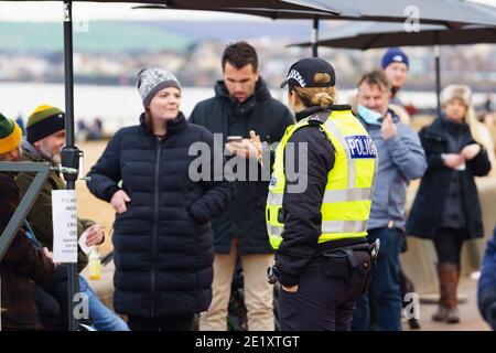 Portobello, Schottland, Großbritannien. 10. Januar 2021. Trotz einer derzeit in Schottland erzwungenen nationalen Sperre waren Portobello Promenade und Strand mit einer großen Anzahl von Menschen beschäftigt, die dort am Sonntagnachmittag waren. Mehrere Polizeipatrouillen waren offensichtlich, dass sie meist unauffällig blieben, aber die Beamten sprachen mit den Kaffeehäffern, um sie zu drängen, die soziale Distanz zwischen den Kunden korrekt zu halten. PIC; die Polizei spricht mit Cafe-Kunden, um die Anforderungen an soziale Distanzierung zu erklären. Iain Masterton/Alamy Live News Stockfoto