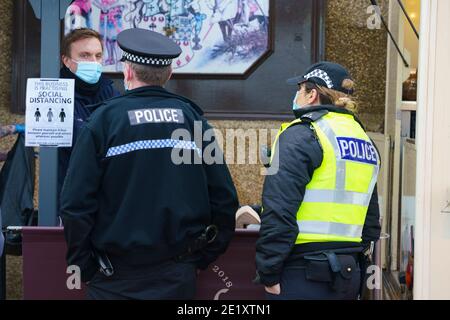 Portobello, Schottland, Großbritannien. 10. Januar 2021. Trotz einer derzeit in Schottland erzwungenen nationalen Sperre waren Portobello Promenade und Strand mit einer großen Anzahl von Menschen beschäftigt, die dort am Sonntagnachmittag waren. Mehrere Polizeipatrouillen waren offensichtlich, dass sie meist unauffällig blieben, aber die Beamten sprachen mit den Kaffeehäffern, um sie zu drängen, die soziale Distanz zwischen den Kunden korrekt zu halten. PIC; die Polizei spricht mit dem Manager des Cafés, um die soziale Distanzierung zu erklären. Iain Masterton/Alamy Live News Stockfoto